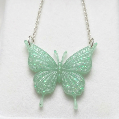 Green butterfly necklace on a white background